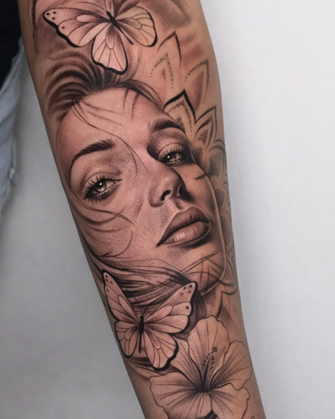 Portrait de femme entouré de papillons et de fleurs, sur l’avant-bras